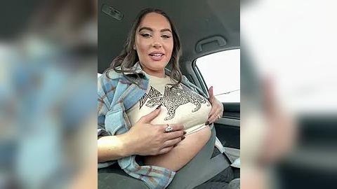 Media: Video of a smiling, curvy Latina woman with medium brown skin, long brown hair, wearing a plaid shirt, exposing a leopard-print bra and holding a phone, seated in a car.