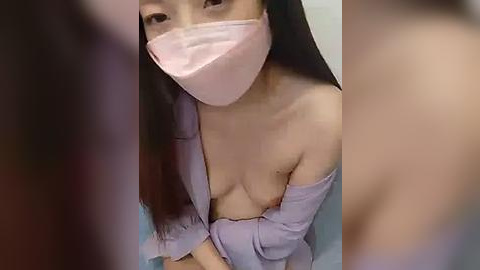 Media: Video of an East Asian woman with long black hair, wearing a pink mask and a purple robe, revealing her bare breasts and nipples.