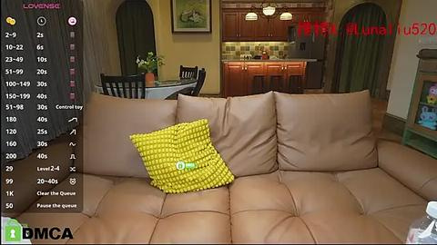 Media: A video of a cozy living room with a beige sectional sofa, yellow patterned pillow, wooden kitchen in the background, and a live video feed overlay.