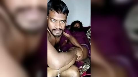 Media: Video: A man with short black hair and a beard, wearing a purple shirt, hugs a woman with long dark hair, wearing a purple saree. Both appear emotional.