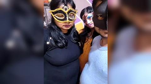 Media: Video of three women wearing black masks with gold accents and long black hair, indoors, blurry background.