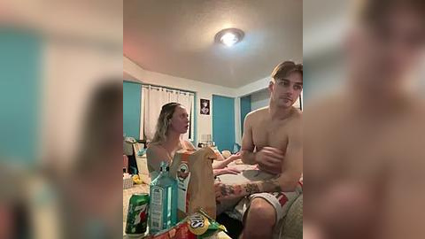 Media: A candid video of two shirtless, tattooed young men in a messy bedroom, one holding a phone, the other sitting on a bed.