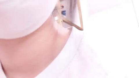 Media: A close-up video of a woman's bare upper chest and neck, with fair skin, wearing a white shirt with a gold pin. The image focuses on the texture and softness of the fabric.