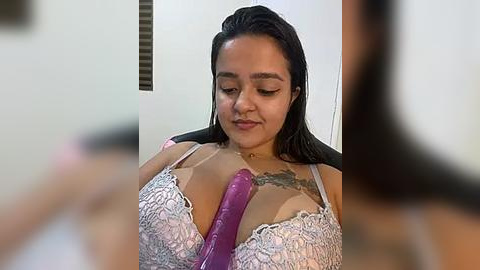 Media: A video of a Latina woman with medium skin tone, wet black hair, wearing a white lace bra, inserting a large purple dildo into her cleavage. The background is blurred.