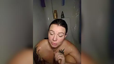 Media: A video of a fair-skinned woman with wet hair, large breasts, and visible tattoos, kissing a small dog in a shower with shampoo bottles and a towel.