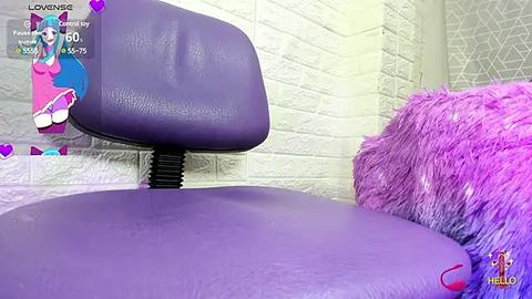 Media: Video of a purple office chair with a black base against a white brick wall. A pink and blue plush doll sits on the chair, and a purple furry pillow rests on the right.