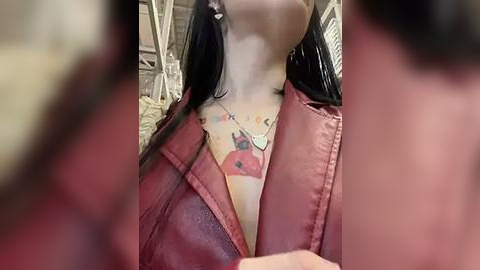 Media: Video of a woman with long black hair, wearing a red leather jacket, revealing a colorful tattoo of a red devil on her chest.