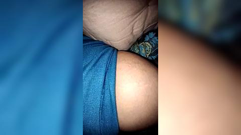Media: A close-up video of a person's arm and torso, showing skin texture and a blue shirt sleeve. The background is blurred, with hints of blue and green tones.