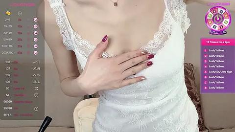 Media: Video of a fair-skinned woman in a white lace camisole, covering her chest with her left hand, with maroon nails. Background features a digital clock and a \"Lust Toy\" app interface.