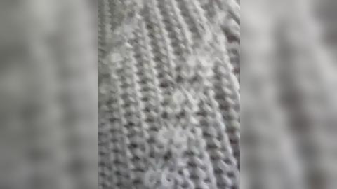 Media: Video of a close-up of a textured, white, woven fabric with a tightly knit, repetitive pattern, displaying a soft, slightly fuzzy texture. The background is blurred, focusing attention on the fabric's intricate details.