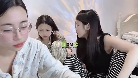 Media: Video of three young East Asian women in a bedroom; one with glasses, one in striped pajamas, and one in a black top.