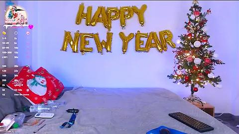 Media: Video of a festive bedroom with a \"Happy New Year\" banner, a decorated Christmas tree, a red Santa hat, and a keyboard on a bed.