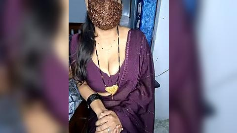 Media: A video of a woman wearing a purple sari with a plunging neckline, revealing cleavage, and a brown headscarf. She has medium skin tone and long black hair.