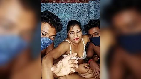 Media: Video of three South Asian women in a tiled room; one in a white bra, one in a blue face mask, and another in a black mask, all with dark skin.