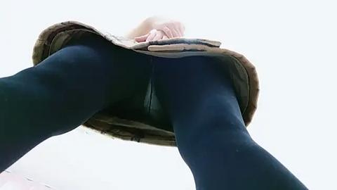 Media: Video of a person's legs in blue tights, beige skirt lifted, revealing black underwear. View from below, highlighting the legs' curves.