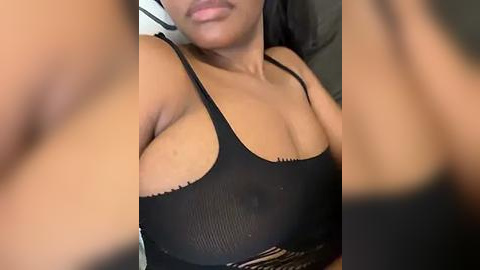 Media: Video of a light-skinned woman with medium-sized breasts wearing a black, sheer tank top that reveals her nipples, taken from a slightly blurred perspective.