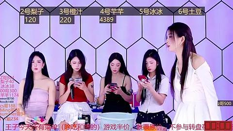 Media: Video of five Asian women, four seated, one standing, at a game show with hexagonal LED background, displaying scores. Women wear casual, colorful outfits; one holds a phone.