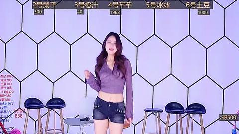 Media: Video of an East Asian woman with long black hair, wearing a purple crop top and denim shorts, standing in front of a purple and white hexagonal-patterned wall.