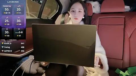 Media: Video of a woman in a car, wearing a white fur coat, using a tablet while reclining in a red leather seat.