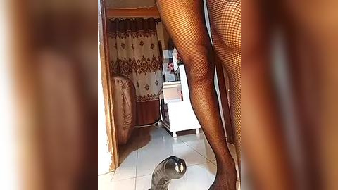 Media: A video shows a person's legs in fishnet stockings and high heels, standing in a dimly lit room with a mirror on the floor, reflecting the person's legs.