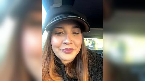 Media: Video of a young woman with long, straight brown hair and a black motorcycle helmet, wearing a black jacket and smiling inside a car.