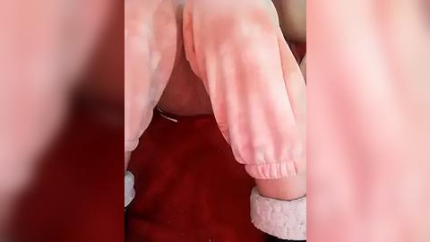 Media: Video of a close-up of a person's bare buttocks, with a hand gently caressing the skin. The background features a red fabric surface.