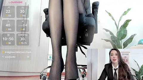 Media: Video of a petite woman in a black office chair, legs in sheer black stockings, with a potted plant in the background, and a calendar showing 40% humidity.