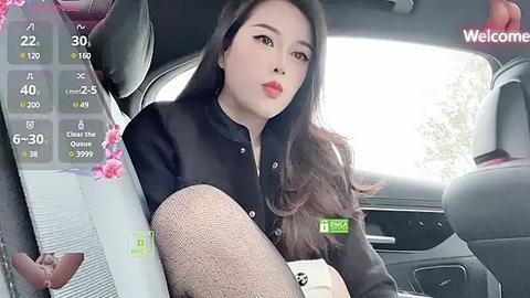 Media: A video of an Asian woman with long, wavy black hair, wearing a black shirt and sheer black tights, seated in a car.