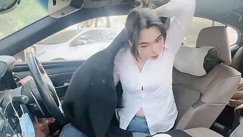 Media: Video of a young East Asian woman with black hair in a white blouse, sitting in a car with a large, black dog in the backseat, driving in a suburban area.