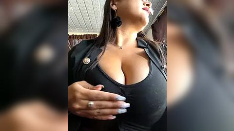 Media: Video of a curvy Latina woman with large breasts in a tight black tank top, wearing a black blazer and black earrings. She has a confident, alluring expression.