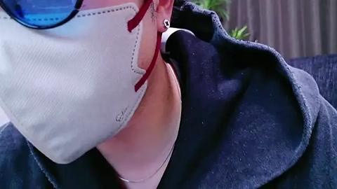 Media: Close-up video of a person's upper body, showcasing a white shirt with a pink collar, a black jacket, and blue sunglasses.