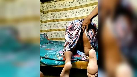 Media: Video of a person in a colorful, floral-patterned dress, pulling up the dress to reveal bare feet and legs. Background includes a striped wall and a turquoise bed with a pillow.