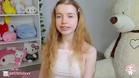 Media: Video of a fair-skinned, long-haired teenage girl in a white polka-dot dress, smiling in a plush-filled room with plush toys and a large bear.