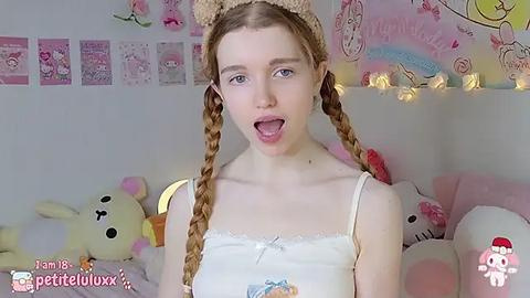 Media: Video of a fair-skinned, young woman with long, braided, light brown hair, wearing a white camisole, and a beige bear headband. Background features plush toys, pastel decorations, and a \"Petite Lulu\" watermark.