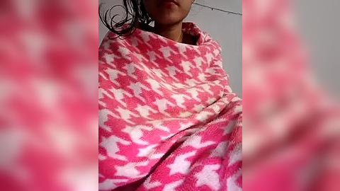 Media: Video of a person wrapped in a pink and white polka-dotted towel, with wet, dark hair visible, indoors against a blurred, light-colored background.