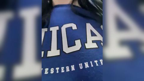 Media: Video of a person wearing a blue, long-sleeved shirt with white text that reads \"UNIVERSITY\" and \"EASTERN\" on the chest. The shirt is slightly wrinkled, and the background is blurred.