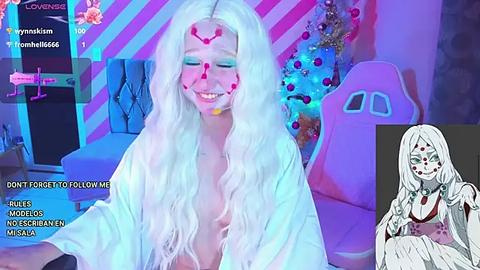 Media: A digital video of a young woman with long, wavy white hair, wearing a light robe, smiling with pink makeup on her face. Background features a pink and blue striped wall and a gaming chair.