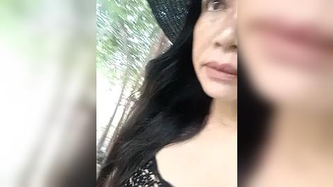Media: A video of a woman with long, dark hair, wearing a black sequined dress, and a black hat, partially visible in the blurred background.