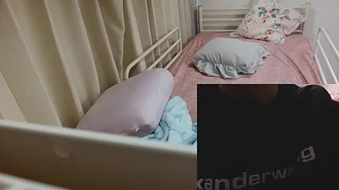 Media: Video of a small, neat bunk bed with pink and white linens, two pillows, and beige curtains in a cozy room.