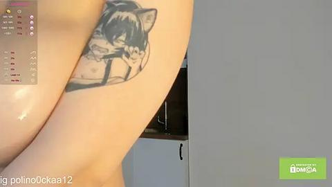 Media: Video of a woman's upper torso with a tattoo of a stylized wolf's head on her left shoulder. Background shows a simple room with a window.