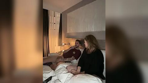 Media: A video of a couple in bed, dimly lit, with the man in a maroon shirt and woman in black, both with light skin, discussing something intimate.