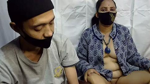 Media: Video of a man with a beard and turban, and a woman with a mask and patterned top, sitting close in a hospital setting.