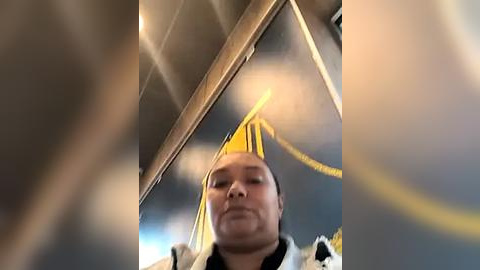 Media: Video of a man with a white headband and a yellow bandana, wearing a white jacket, seated inside a train, with blurred motion blur and yellow streaks in the background.