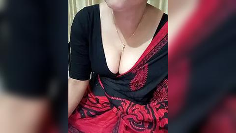 Media: Video of a fair-skinned woman with a large bust in a low-cut black top, adorned with a red and black patterned sari.