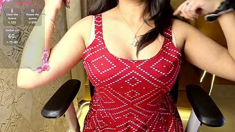 Media: Video of a woman with medium skin tone and long dark hair, wearing a sleeveless red dress with white geometric patterns, adjusting a bracelet on her wrist.