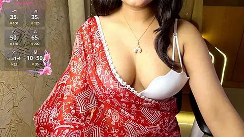 Media: Video of a woman with medium skin tone, wearing a red patterned sarong and a white bra, with a necklace, in an indoor setting with a stone wall and ambient lighting.