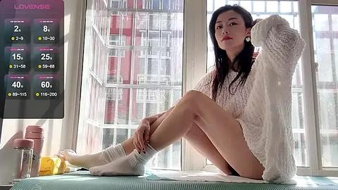 Media: Video of a slender, fair-skinned Asian woman with long black hair, wearing a white sweater and no pants, sitting on a window ledge. She has a relaxed expression.