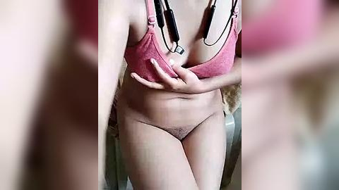 Media: Video of a woman in a pink bra and underwear, standing in a bathroom with a mirror, blurred background, focusing on her body.