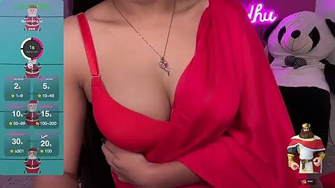 Media: Video of a light-skinned woman wearing a low-cut red dress, with a pendant necklace, in a bedroom adorned with a plush panda and colorful gaming overlay on the left.