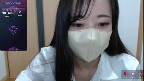 Media: Video of a young Asian woman with long black hair, wearing a white medical mask and white coat, in a clinical setting.